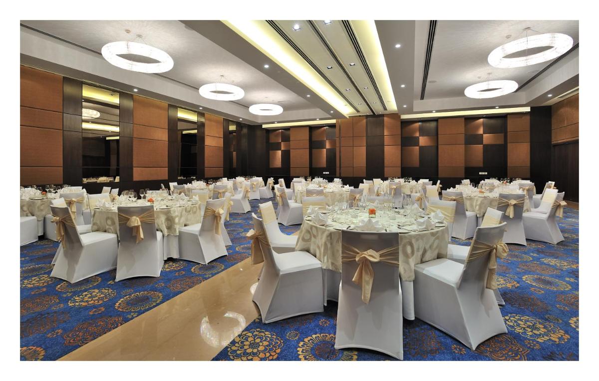 a banquet hall with white tables and white chairs at The Anya Hotel-Golf Course Road in Gurgaon