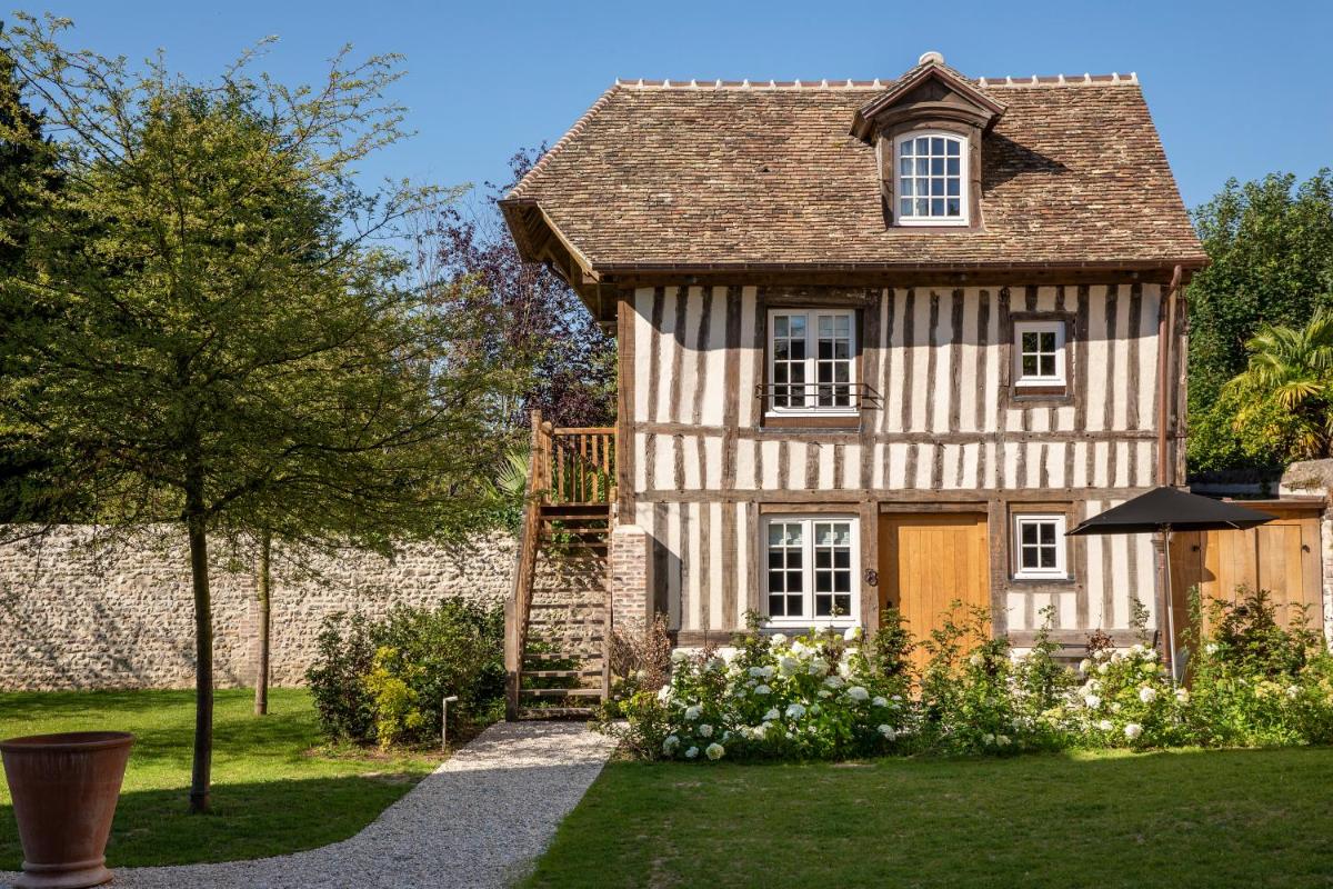 une maison ancienne avec un jardin et un arbre dans l'établissement Hôtel Saint-Delis - La Maison du Peintre - Relais & Châteaux, à Honfleur