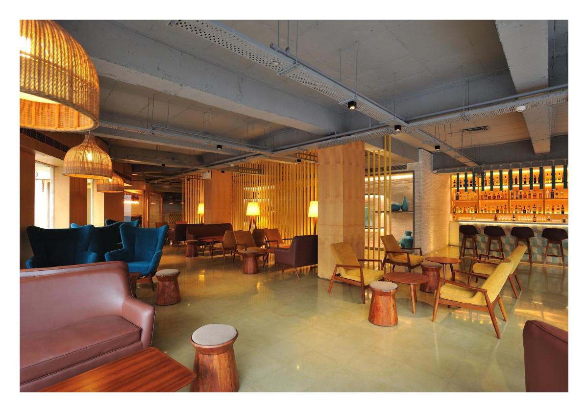 a room with a bar with chairs and tables at The Anya Hotel-Golf Course Road in Gurgaon