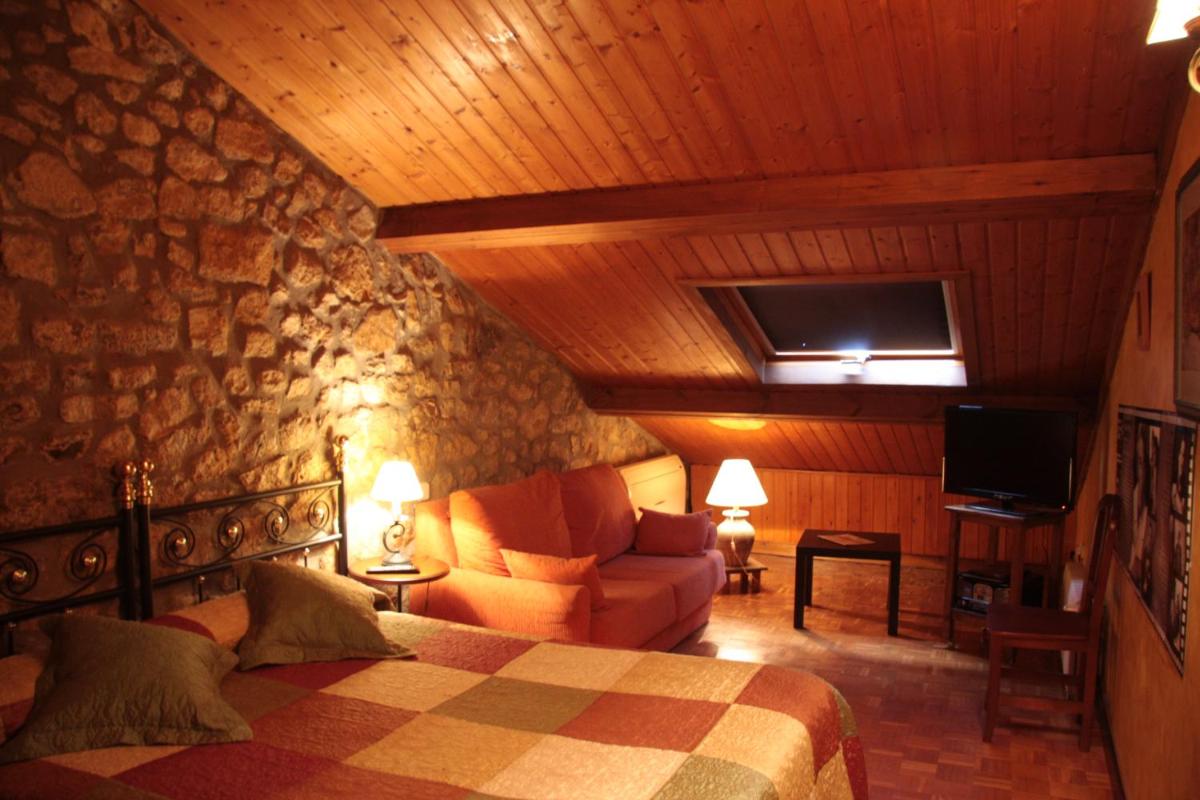 Un dormitorio con una cama, un sofá y un televisor. en Hotel "Posada de Cantabria EL SOLAR" -Cenas típicas y Gintonic- Bar -Terraza panorámica, en Galizano