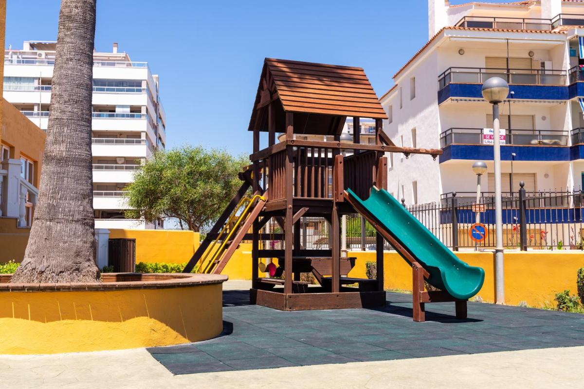 Un parque infantil con un tobogán junto a una palmera en Gran Hotel Peñiscola, en Peñíscola