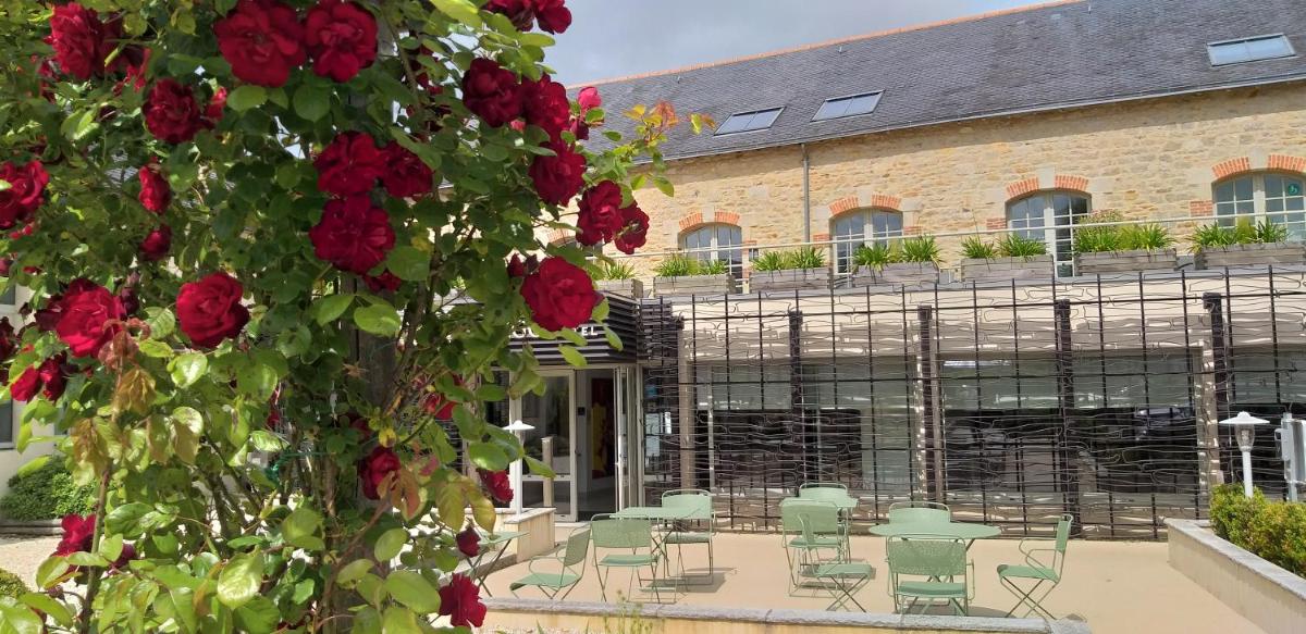 - un bâtiment avec un bouquet de chaises et de roses rouges dans l'établissement Hôtel Ginkgo - SPA Biloba, à Quimper