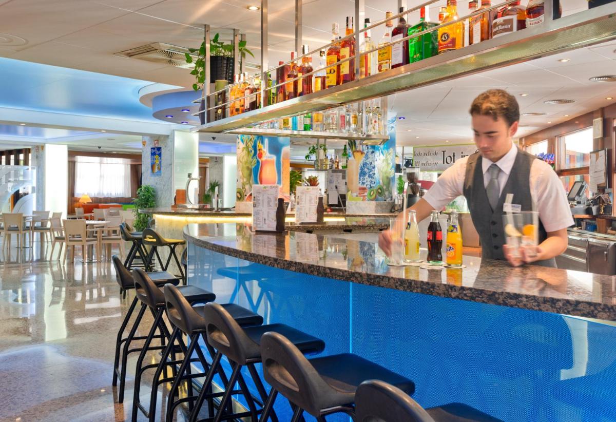 un hombre de pie en un bar preparando una bebida en GHT Oasis Park & Spa, en Lloret de Mar