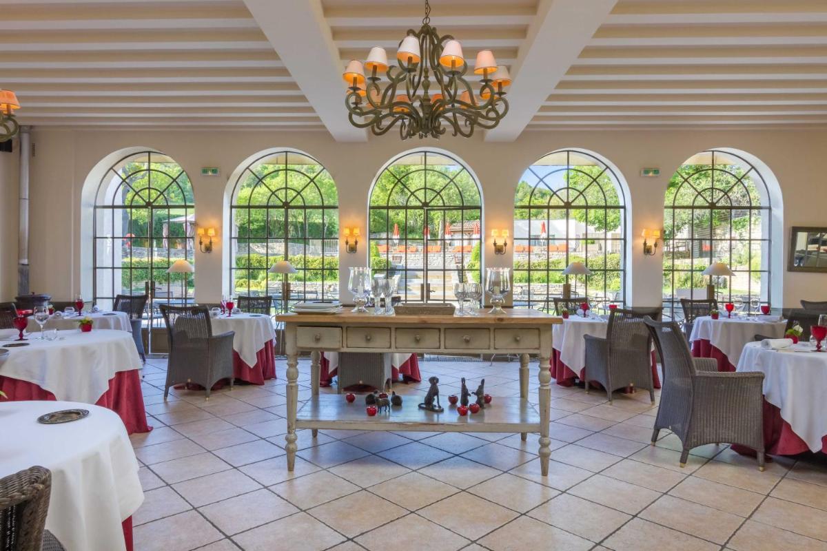 une salle à manger avec tables, chaises et un lustre dans l'établissement Château de Courban and Spa Nuxe, à Courban
