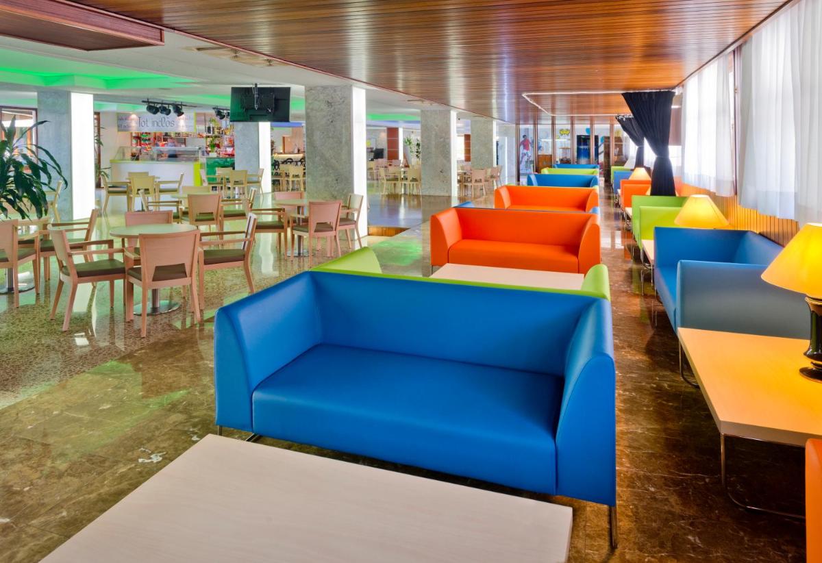 un vestíbulo con muebles coloridos, mesas y sillas en GHT Oasis Park & Spa, en Lloret de Mar