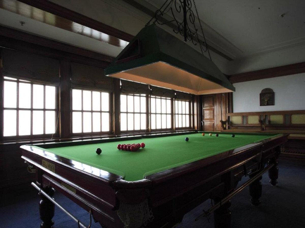 a pool table with balls on it in a room with windows at Jaypee Residency Manor in Mussoorie
