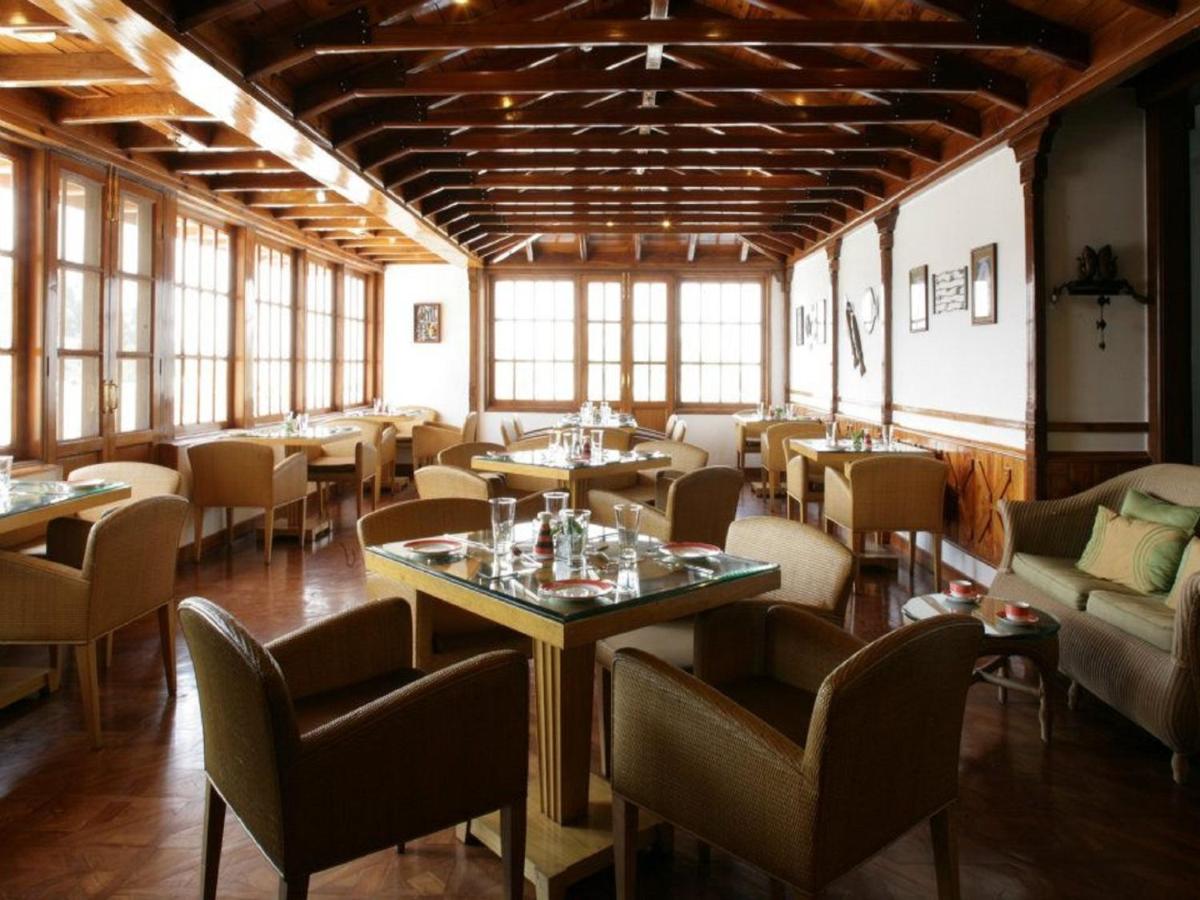 a dining room with tables and chairs and windows at Jaypee Residency Manor in Mussoorie