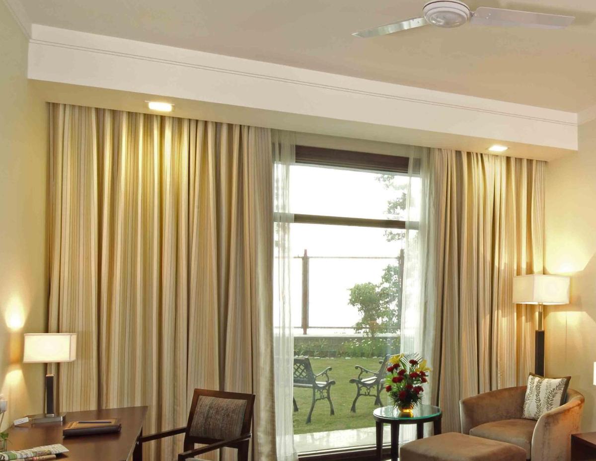 a living room with a large window with curtains at Jaypee Residency Manor in Mussoorie