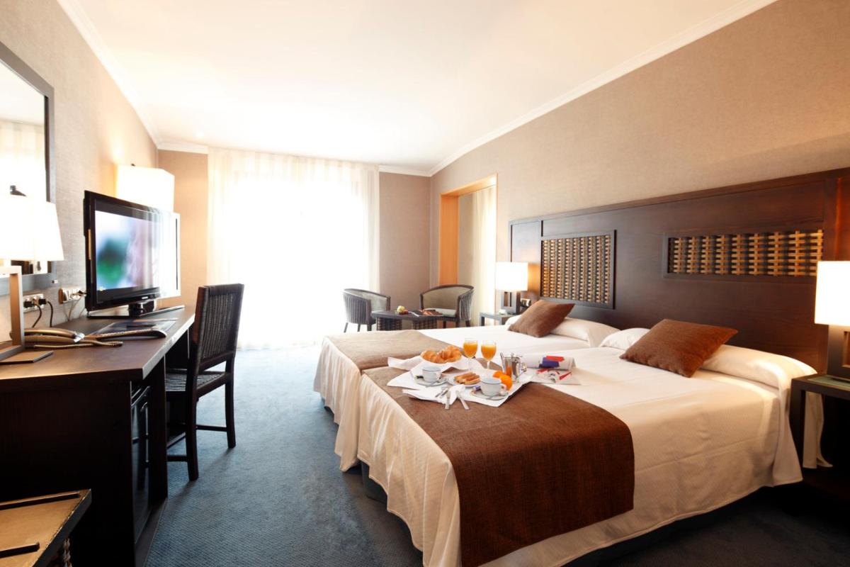 Una habitación de hotel con una cama grande y un escritorio. en Hotel Spa Congreso, en Teo