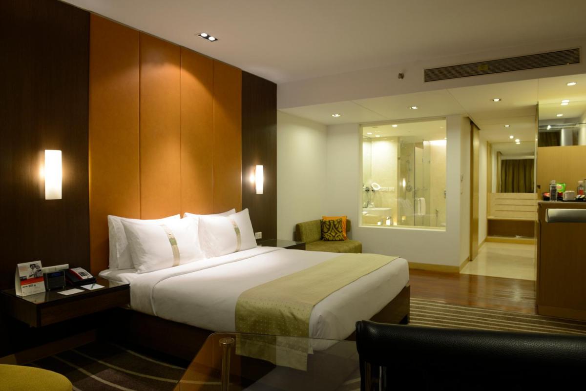 a hotel room with a bed and a chair at Holiday Inn Mumbai International Airport by IHG in Mumbai