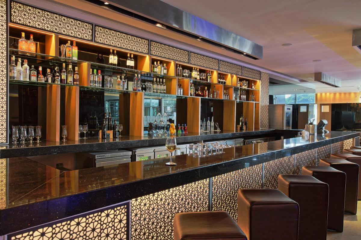 a bar with brown stools in a restaurant at Novotel Pune Viman Nagar Road in Pune