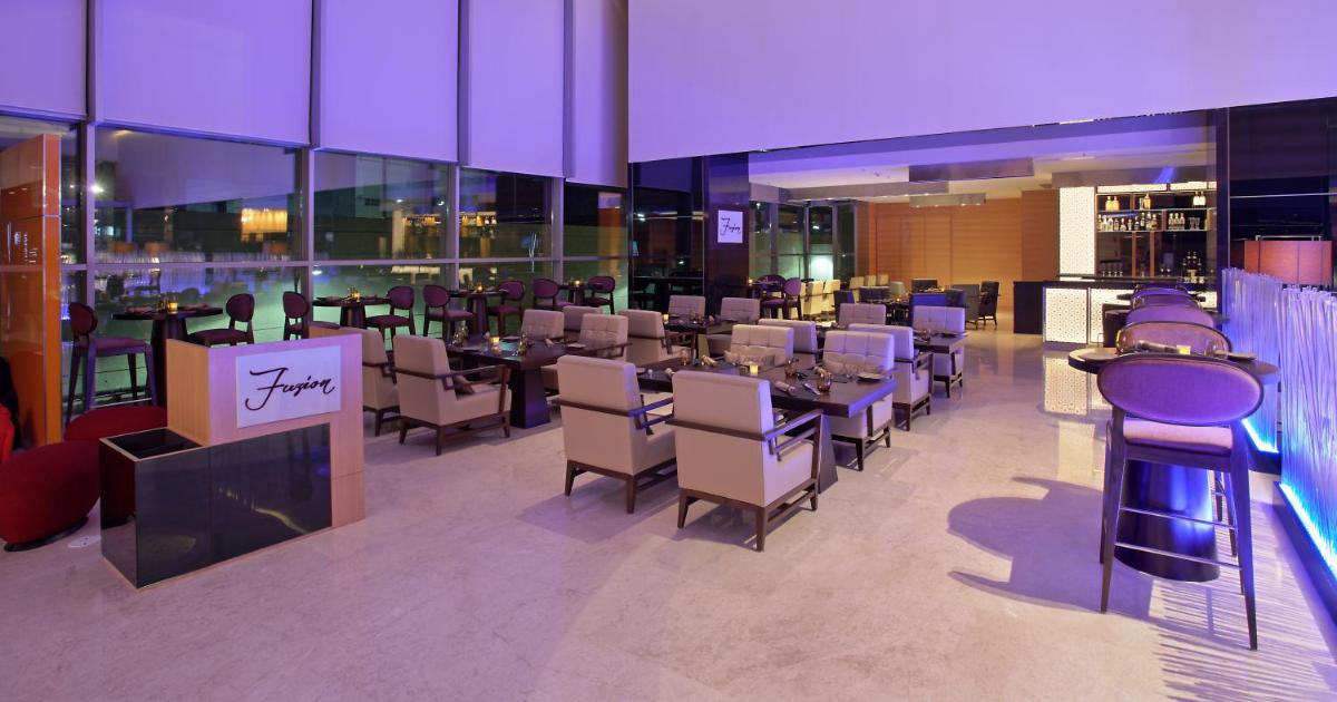 a restaurant with tables and chairs in a building at Novotel Pune Viman Nagar Road in Pune