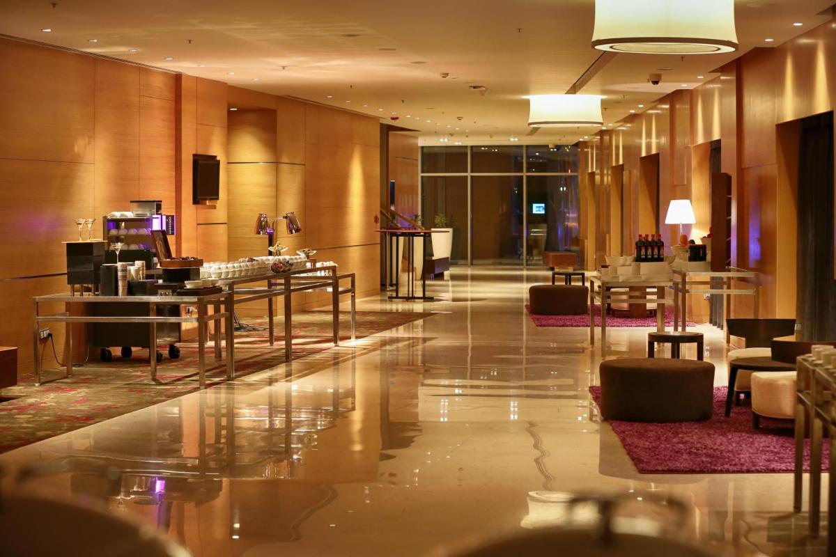 a lobby of a hotel with tables and chairs at Novotel Pune Viman Nagar Road in Pune