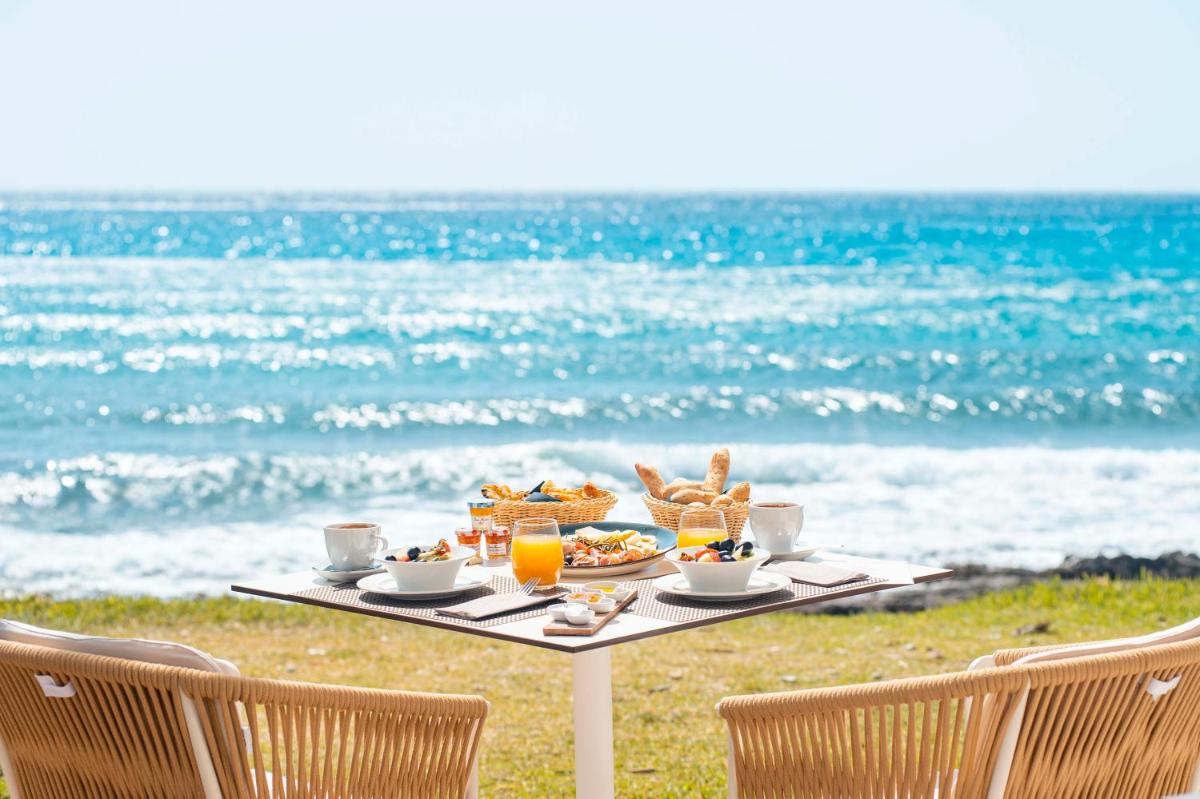 una mesa con comida y bebida en la playa en Melbeach Hotel & Spa - Adults Only, en Canyamel
