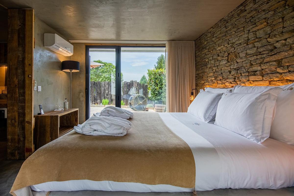 um quarto com uma cama grande com uma parede de pedra em Quinta do Pedregal Hotel & Spa em Vila Nova de Gaia