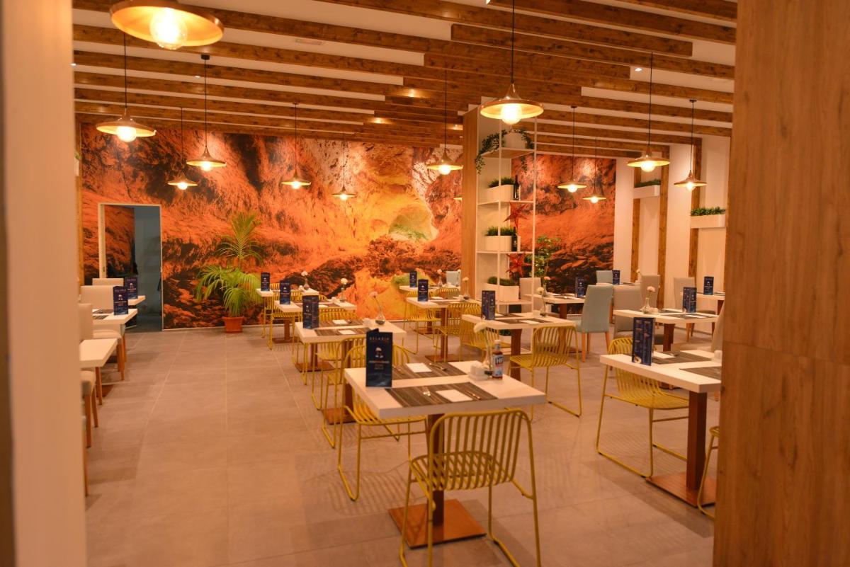 un comedor con mesas, sillas y una pared en Relaxia Lanzasur Club - Aqualava Water Park, en Playa Blanca