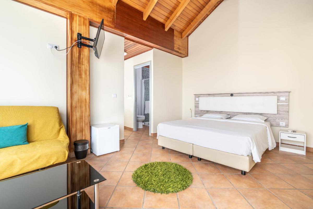 um quarto com uma cama e um sofá em TarmarPlace em Jardim do Mar