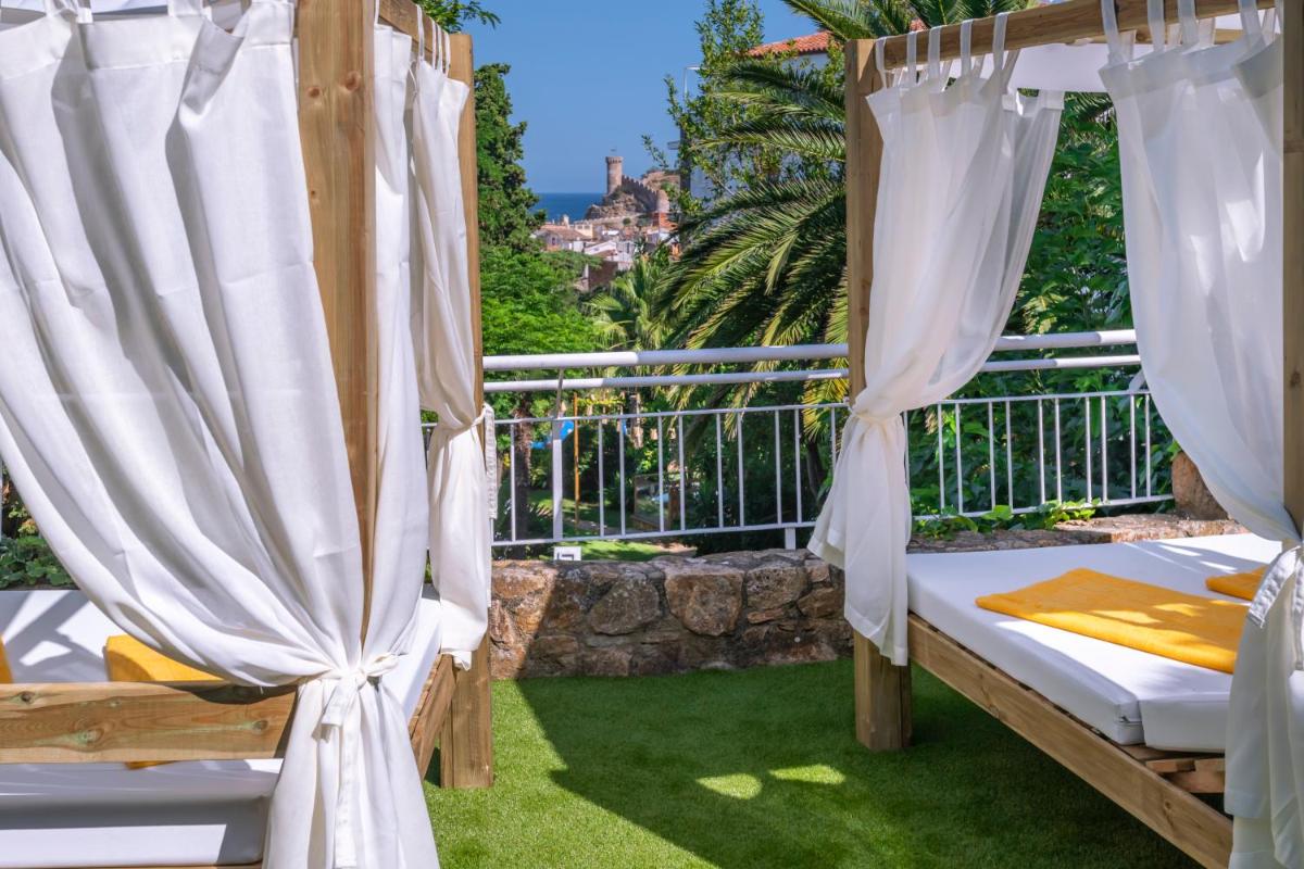Habitación con cama y cortinas en el balcón. en Hotel GHT Neptuno-Tossa & Venus SPA, en Tossa de Mar