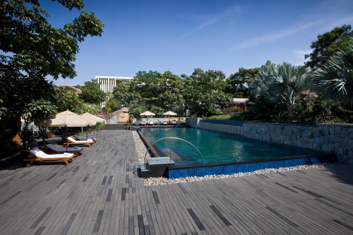 a swimming pool with chairs and umbrellas on a patio at Hyatt Hyderabad Gachibowli in Hyderabad