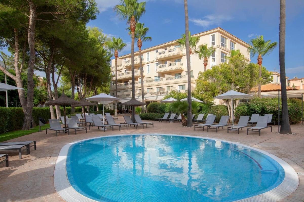 Una piscina con sillas y un edificio al fondo. en HM Mar Blau, en Sa Coma