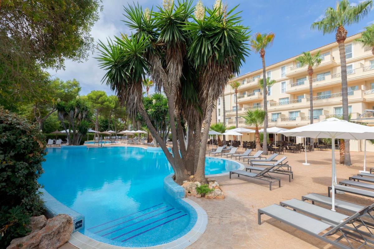 una piscina con tumbonas y una palmera frente a un hotel en HM Mar Blau, en Sa Coma