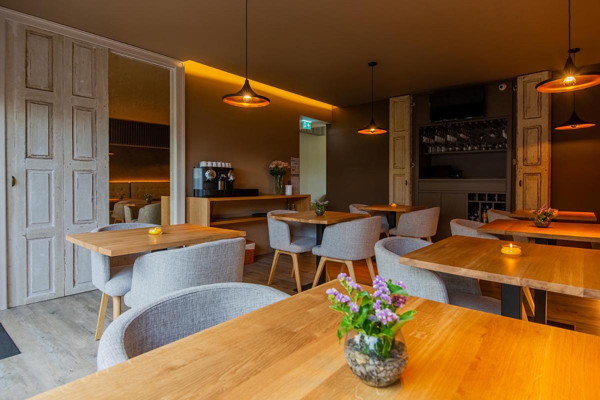 um restaurante com mesas e cadeiras de madeira e flores em Quinta do Pedregal Hotel & Spa em Vila Nova de Gaia