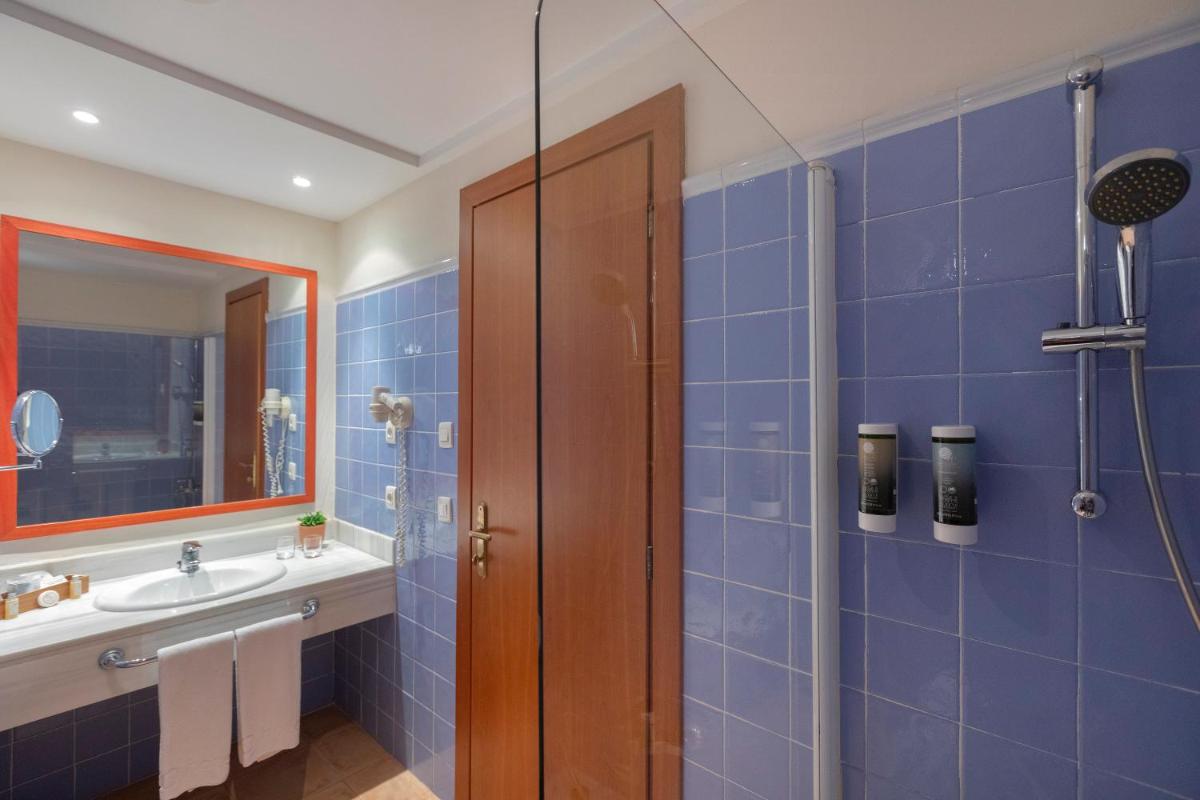 y baño de azulejos azules con lavabo y ducha. en HM Mar Blau, en Sa Coma