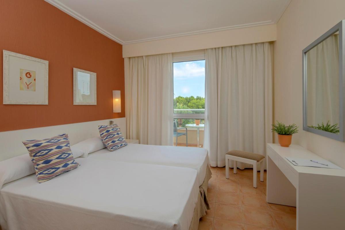 Un dormitorio con una gran cama blanca y una ventana. en HM Mar Blau, en Sa Coma