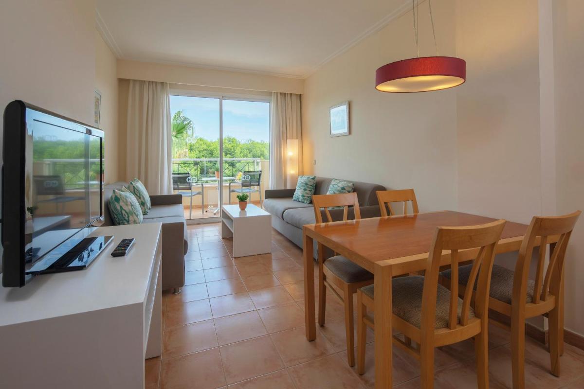 Sala de estar con mesa de comedor y TV en HM Mar Blau, en Sa Coma