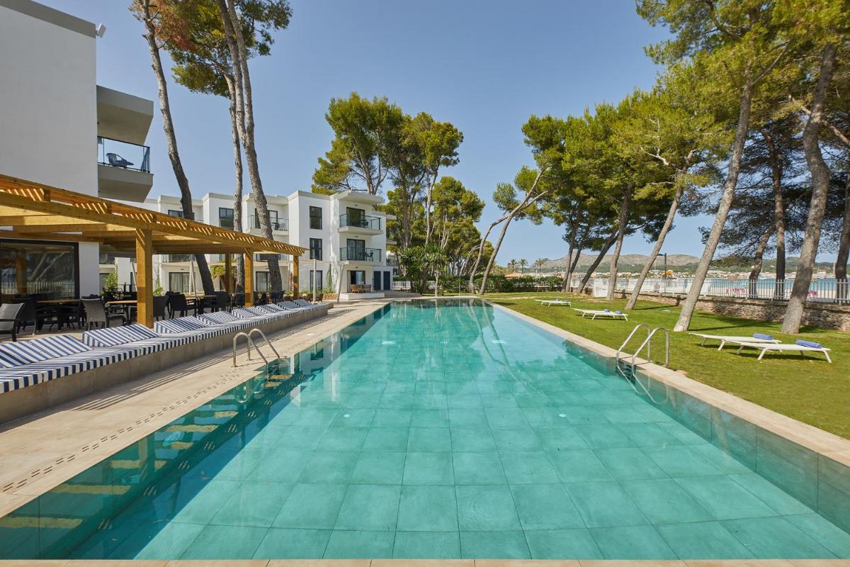 una piscina con sillas y árboles y un edificio en Sofia Alcudia Beach, en Puerto de Alcudia