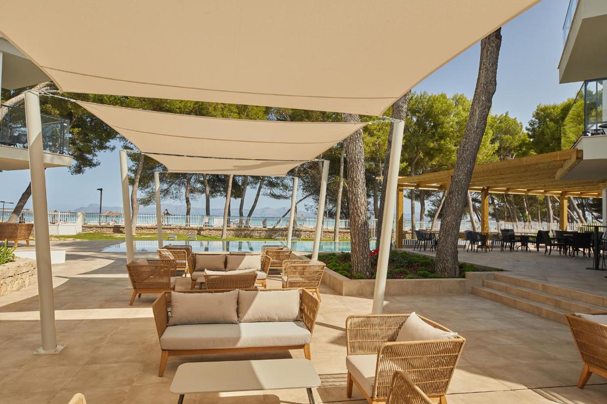 un patio cubierto con sillas, mesas y una tienda de campaña en Sofia Alcudia Beach, en Puerto de Alcudia