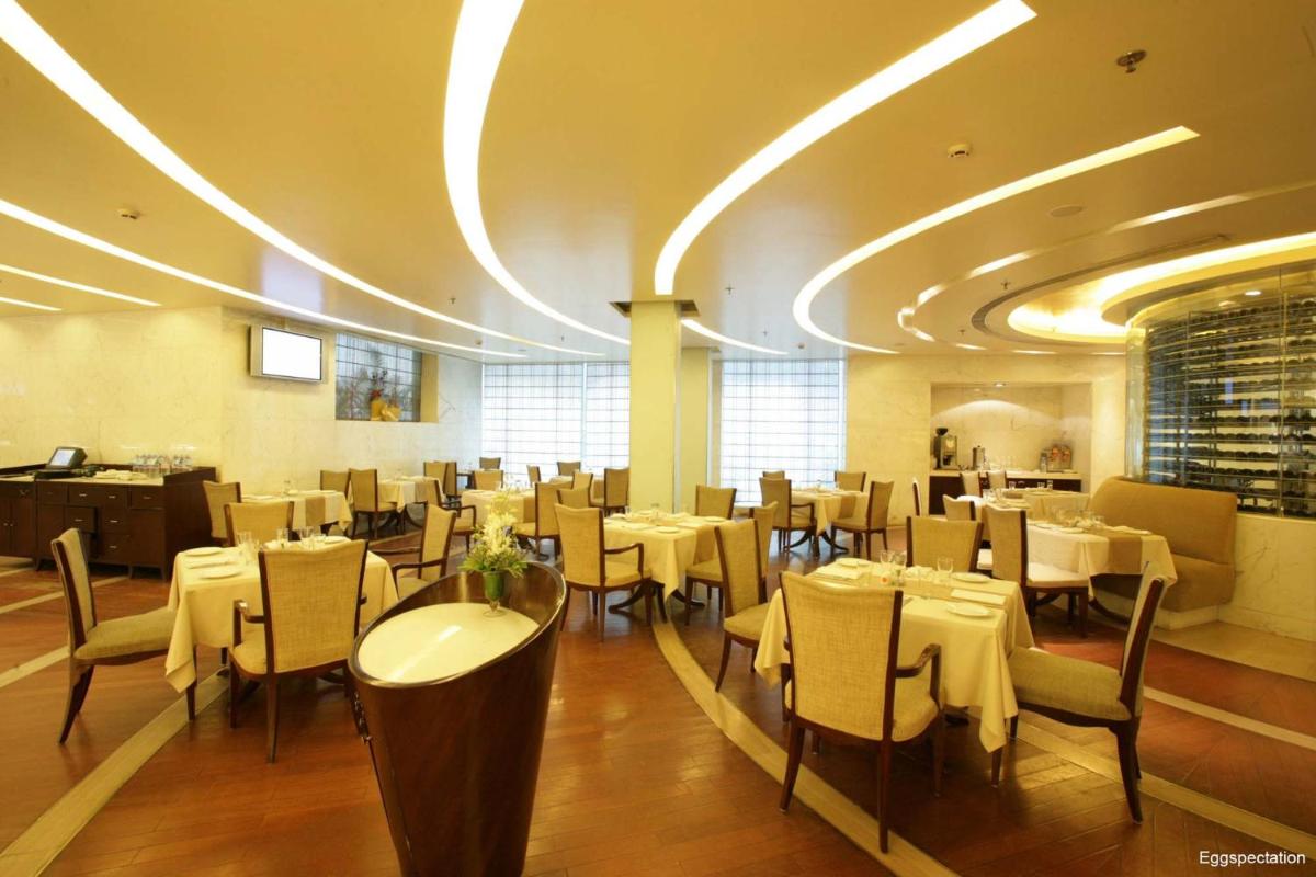 a dining room with tables and chairs in a restaurant at Jaypee Siddharth in New Delhi a dining room with tables and chairs in a restaurant at Jaypee Siddharth in New Delhi