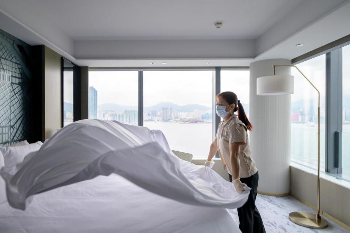 a woman in a mask making a bed in a hotel room at Hyatt Regency Kolkata in Kolkata a woman in a mask making a bed in a hotel room at Hyatt Regency Kolkata in Kolkata
