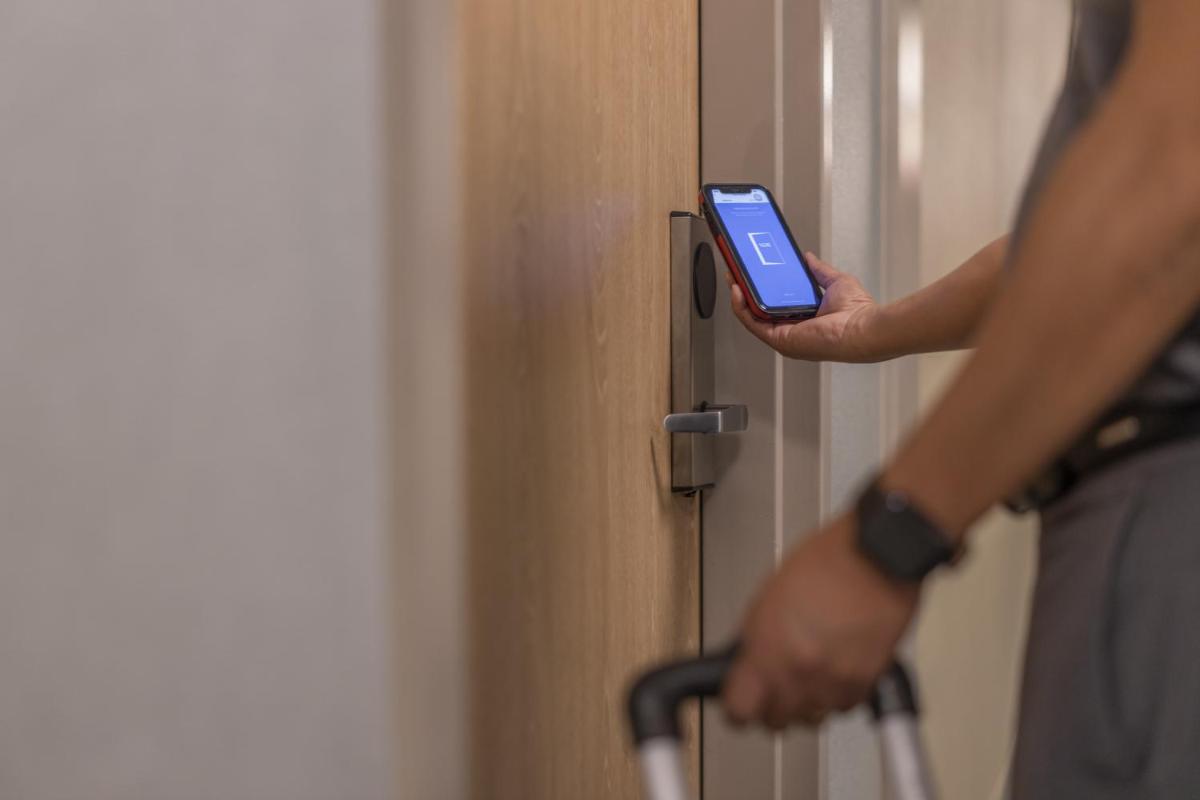 a person holding a cell phone in front of a door at Hyatt Regency Kolkata in Kolkata a person holding a cell phone in front of a door at Hyatt Regency Kolkata in Kolkata