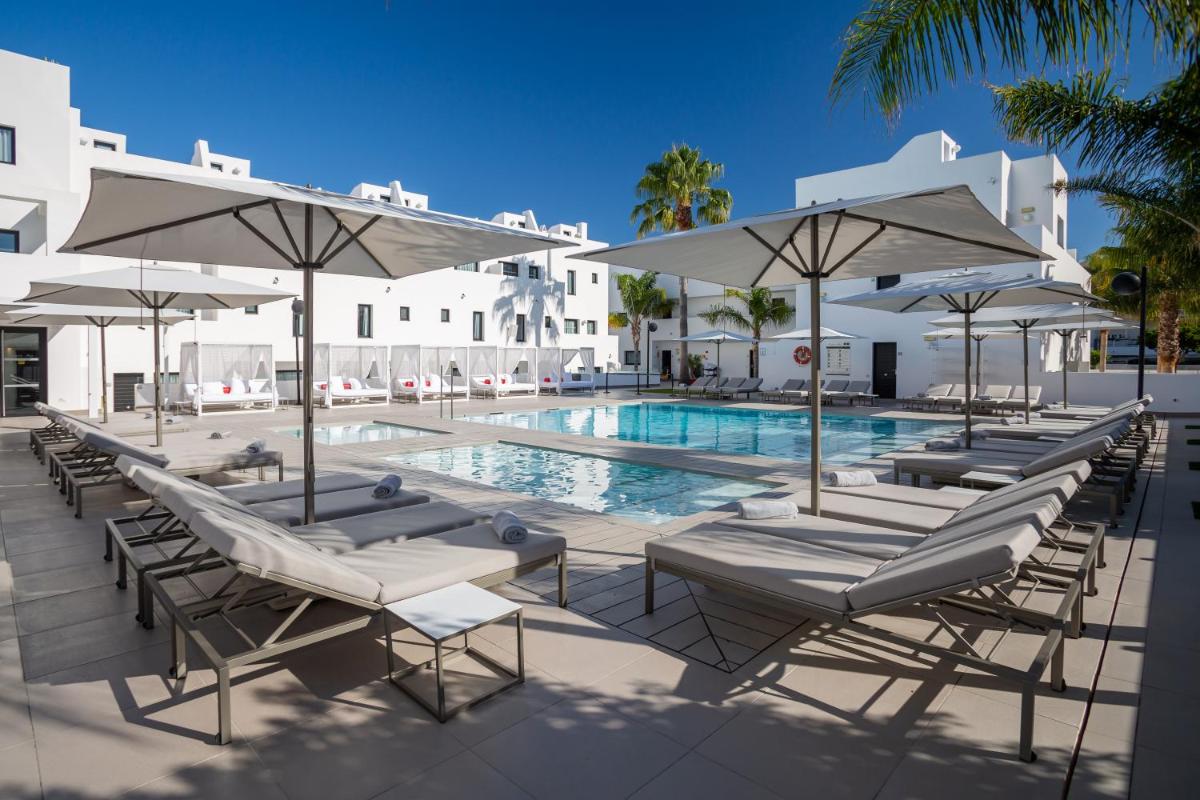 una piscina con tumbonas y sombrillas en Migjorn Ibiza Suites & Spa, en Playa d'en Bossa