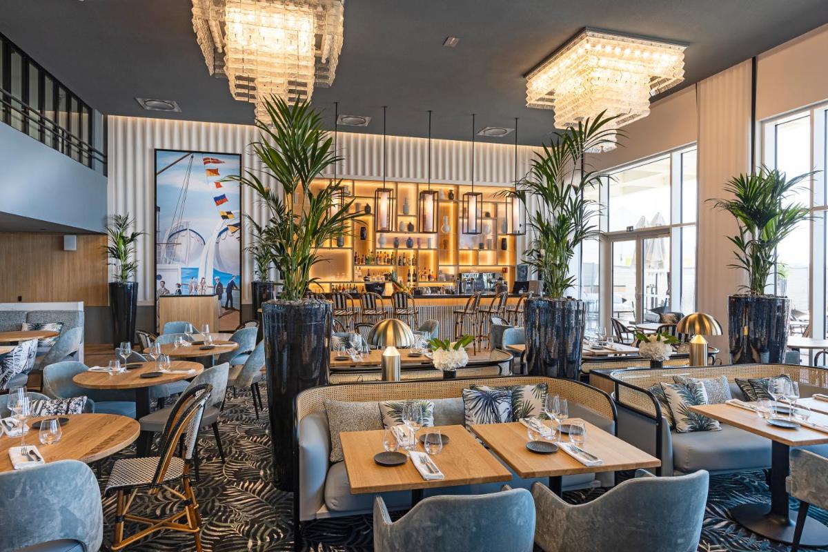 un restaurant avec des tables, des chaises et des lustres dans l'établissement Thalazur Saint Jean de Luz - Hôtel & Spa, à Saint-Jean-de-Luz