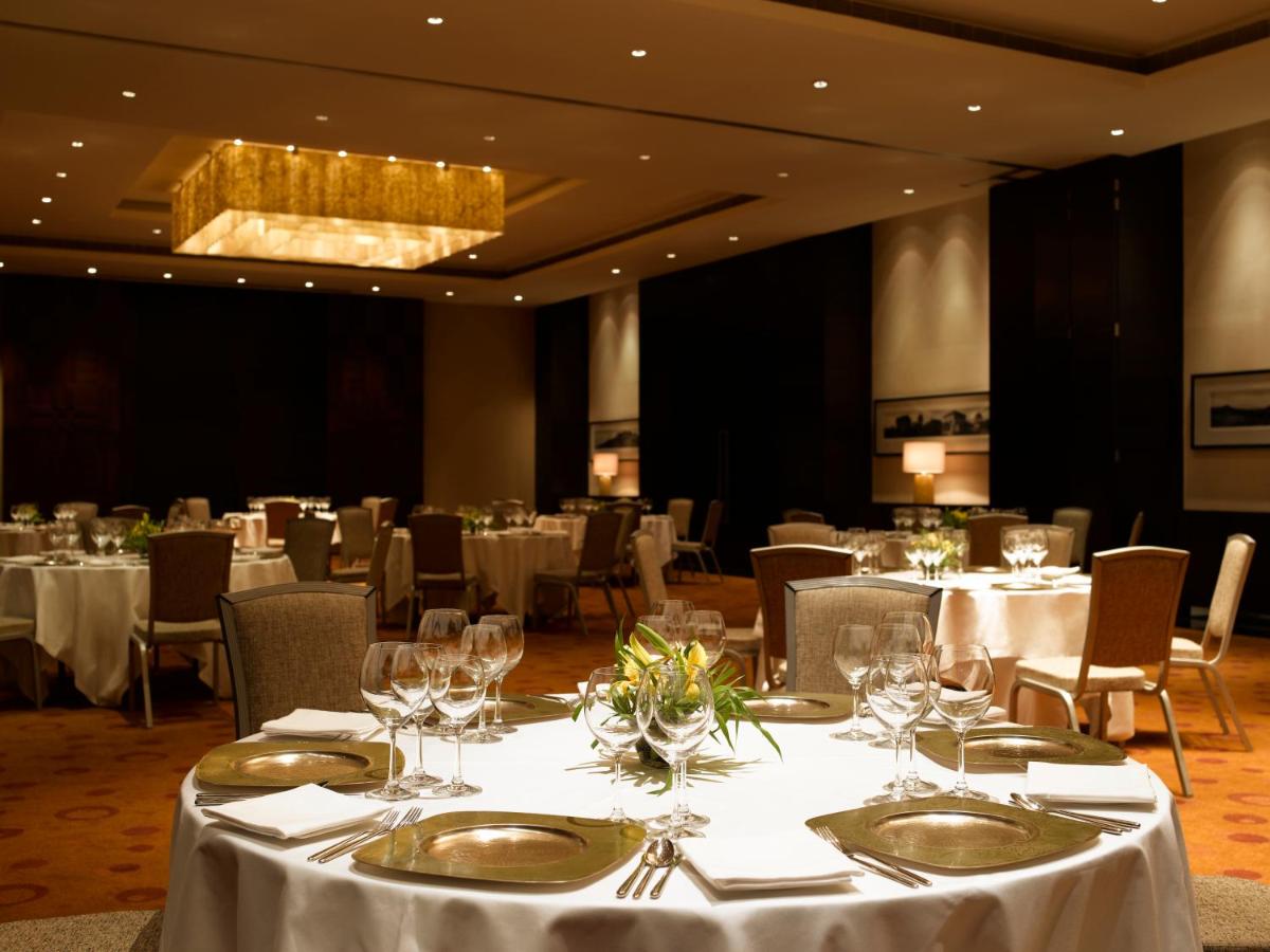 a banquet room with white tables and chairs and a chandelier at Hyatt Hyderabad Gachibowli in Hyderabad