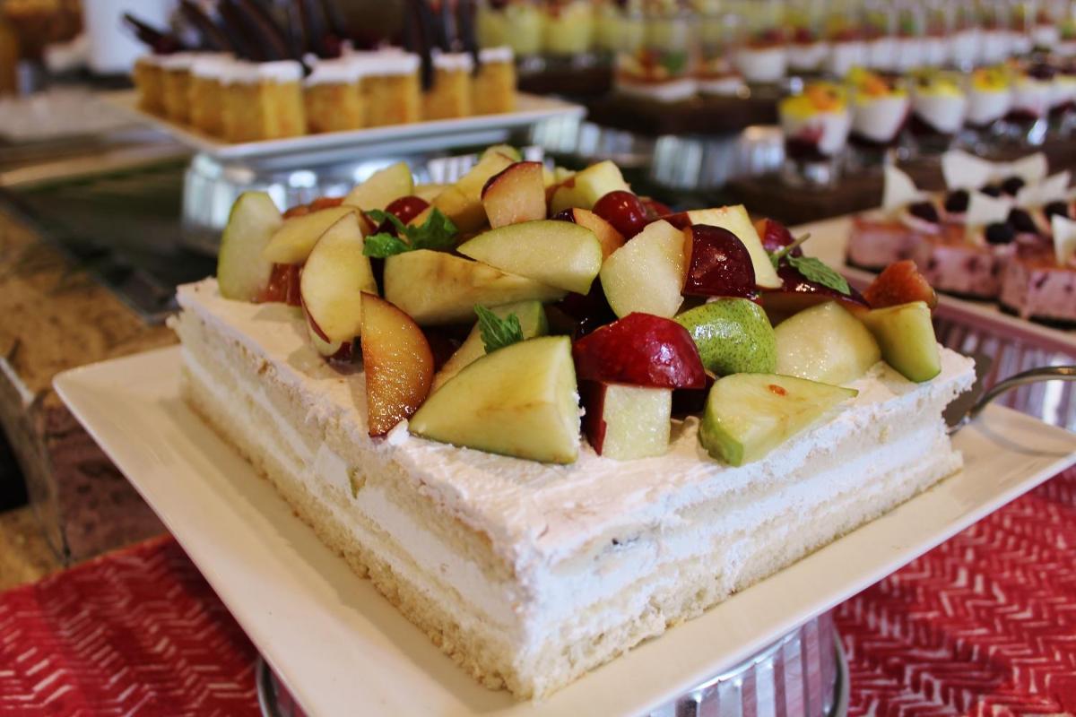 a cake with fruit on top of it on a table at Hyatt Hyderabad Gachibowli in Hyderabad