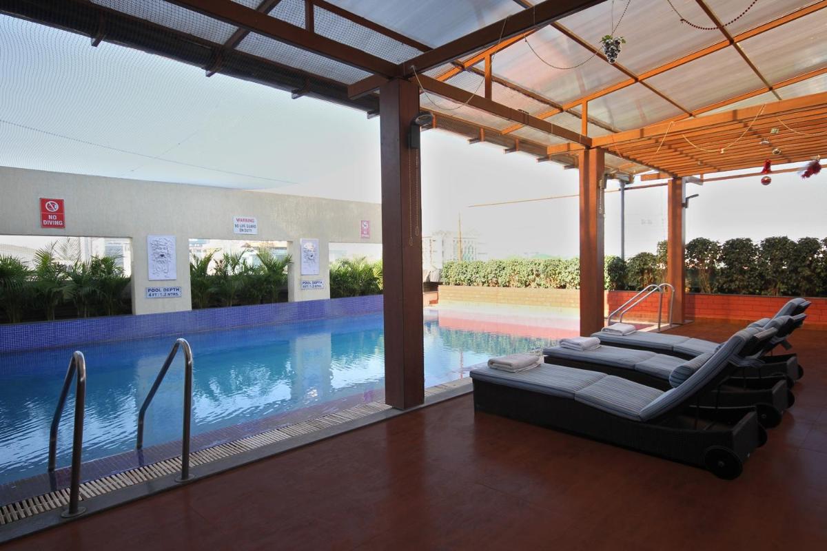 a swimming pool with lounge chairs next to a swimming pool at Fortune Select JP Cosmos, Bengaluru - Member ITC Hotels' Group in Bengaluru a swimming pool with lounge chairs next to a swimming pool at Fortune Select JP Cosmos, Bengaluru - Member ITC Hotels' Group in Bengaluru