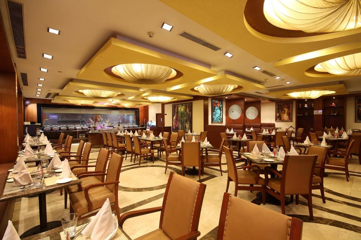 a restaurant with tables and chairs and a large screen at Fortune Select JP Cosmos, Bengaluru - Member ITC Hotels' Group in Bengaluru a restaurant with tables and chairs and a large screen at Fortune Select JP Cosmos, Bengaluru - Member ITC Hotels' Group in Bengaluru