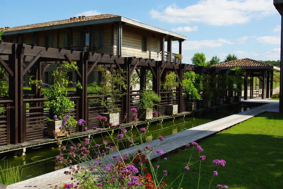 une maison sur un pont sur un étang fleuri dans l'établissement Résidence Les Vignes, à Jonzac