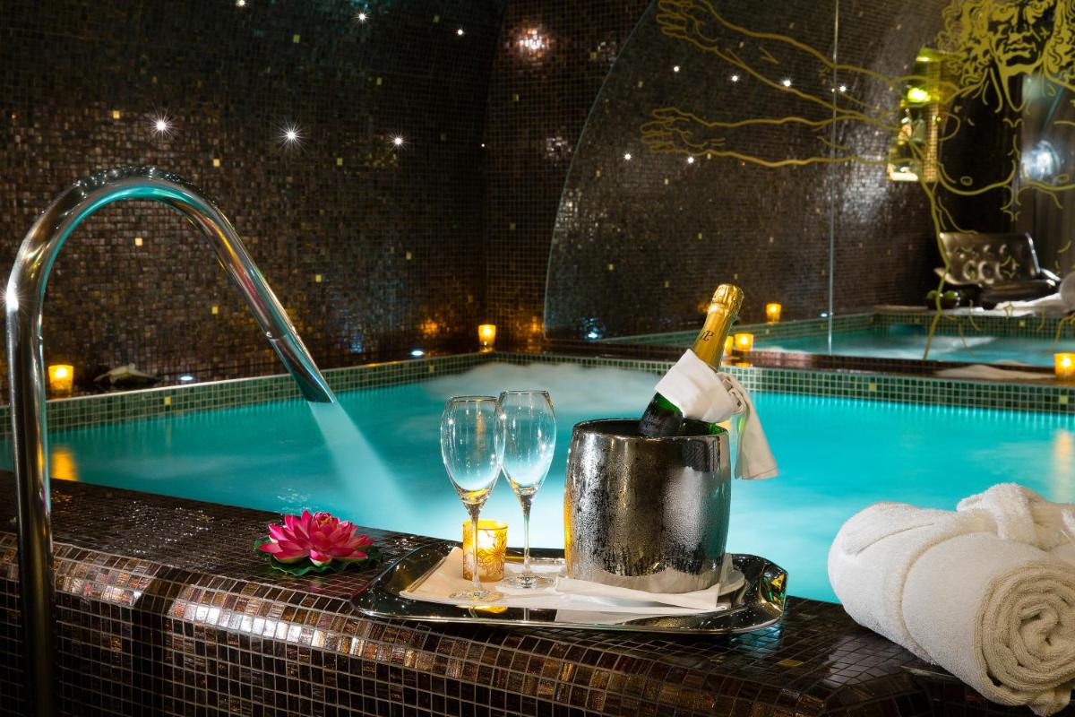 - une table avec une bouteille de vin et des verres à côté de la piscine dans l'établissement Hôtel Da Vinci & Spa, à Paris