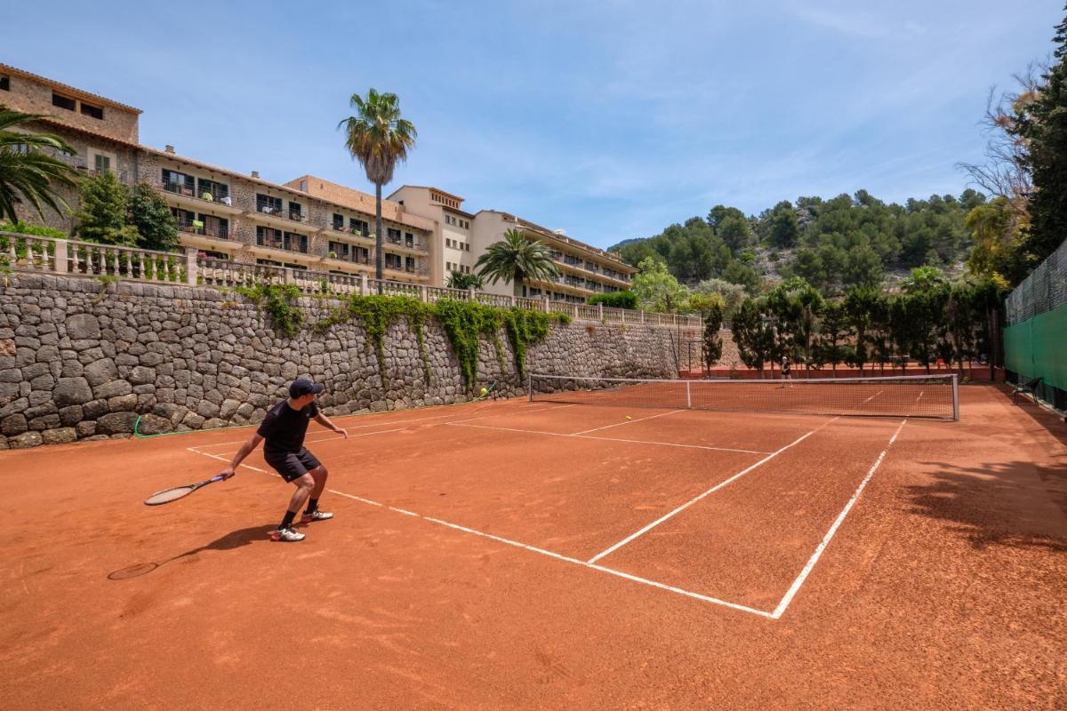 un hombre está jugando al tenis en una pista de tenis en Hotel Es Port, en Puerto de Sóller