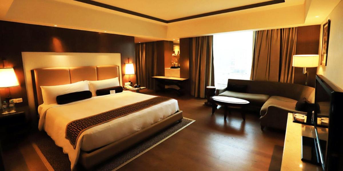 a bedroom with a bed and a living room with a couch at Crowne Plaza New Delhi Okhla by IHG in New Delhi