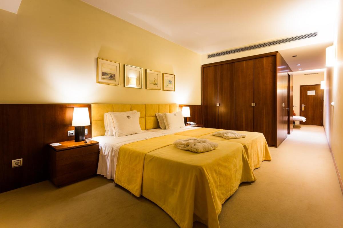 um quarto de hotel com uma cama grande com um cobertor amarelo em Santana Hotel & SPA em Vila do Conde mais 67 fotografias