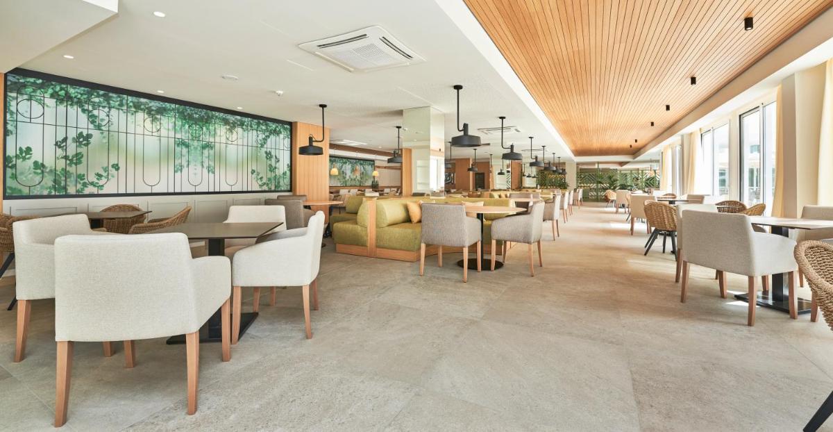 Un restaurante con mesas y sillas y un sofá. en Hoposa Hotel & Apartaments VillaConcha, en Puerto Pollensa
