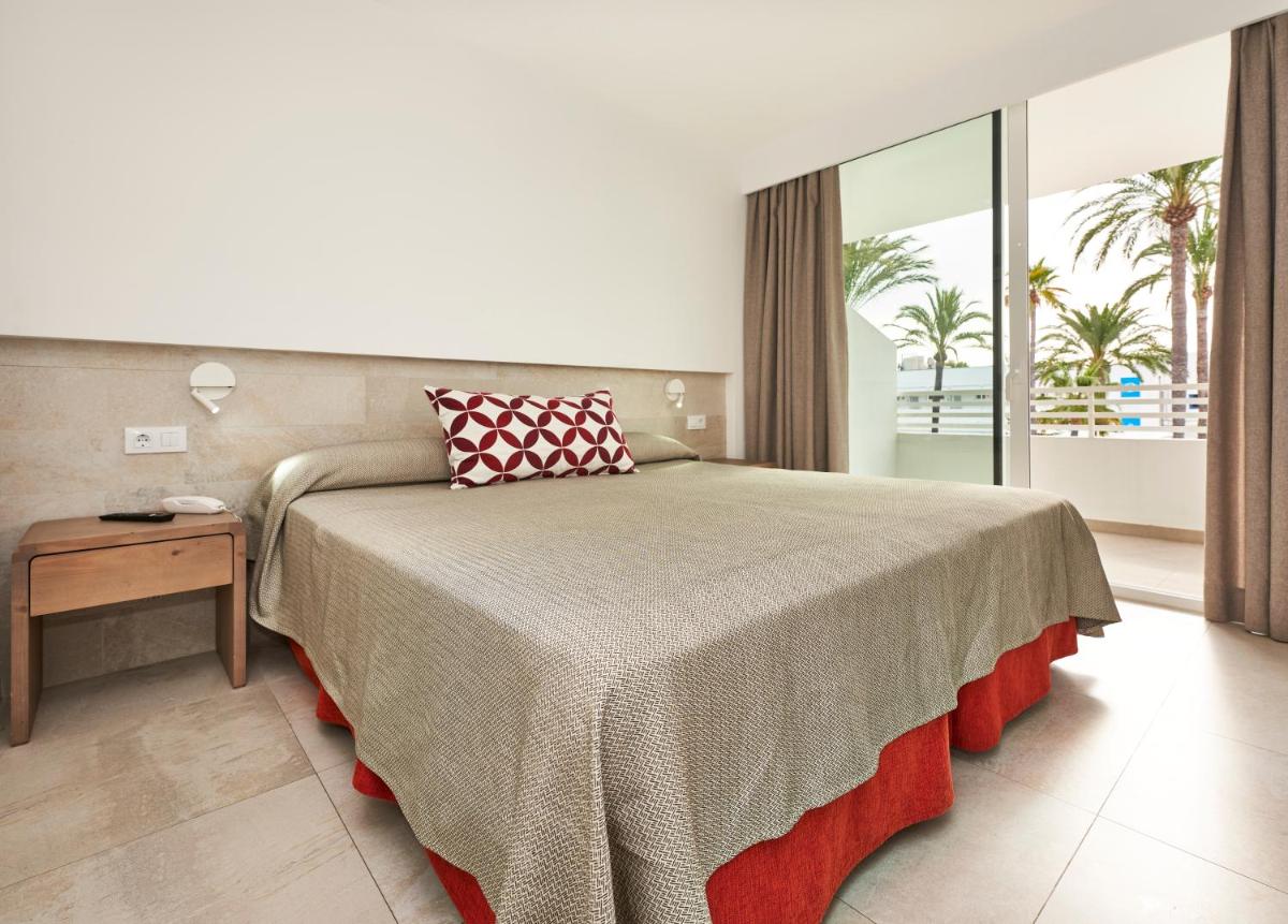 Un dormitorio con una cama y una mesa y una ventana. en Hoposa Hotel & Apartaments VillaConcha, en Puerto Pollensa