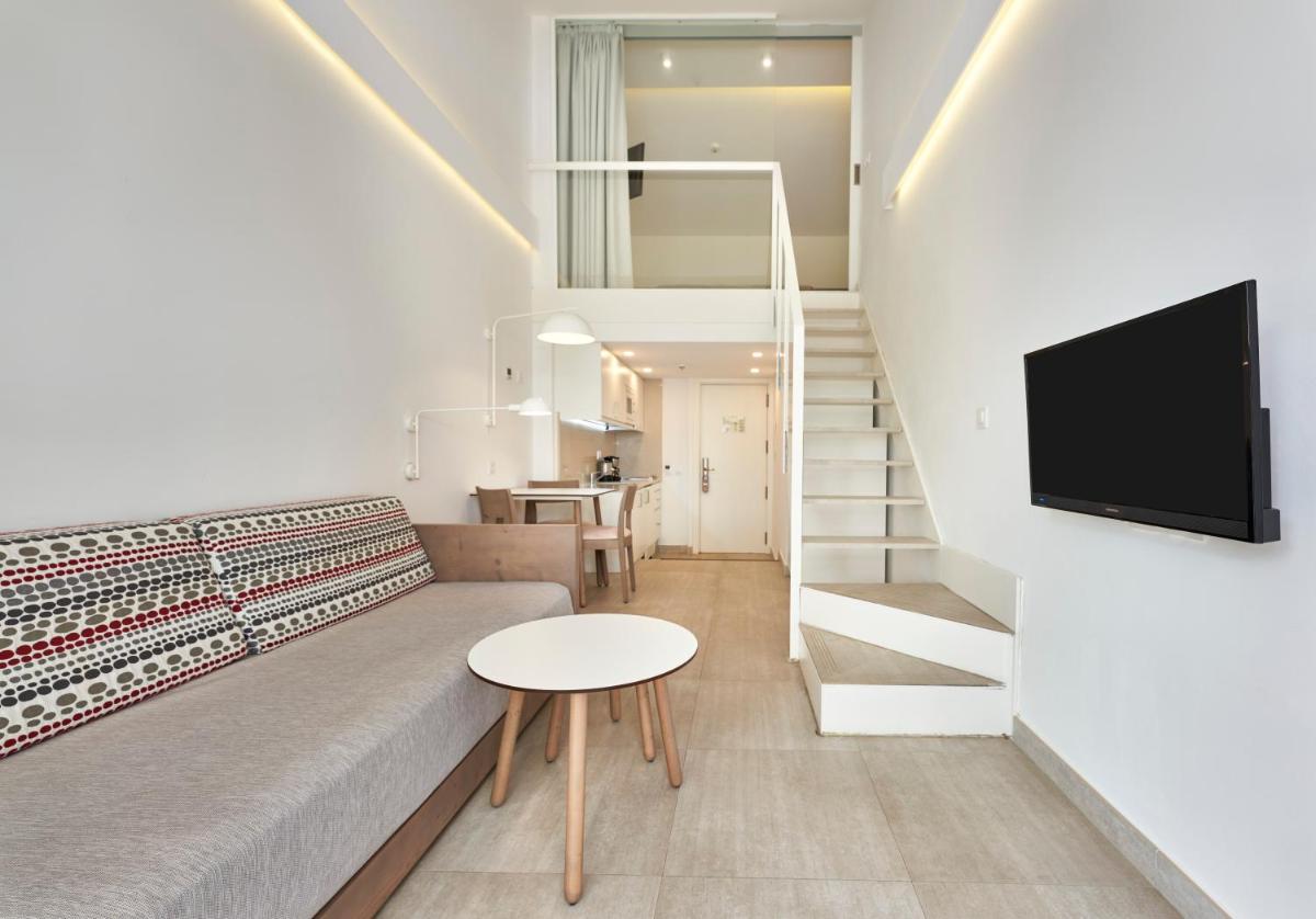 Una sala de estar con un sofá y un televisor. en Hoposa Hotel & Apartaments VillaConcha, en Puerto Pollensa