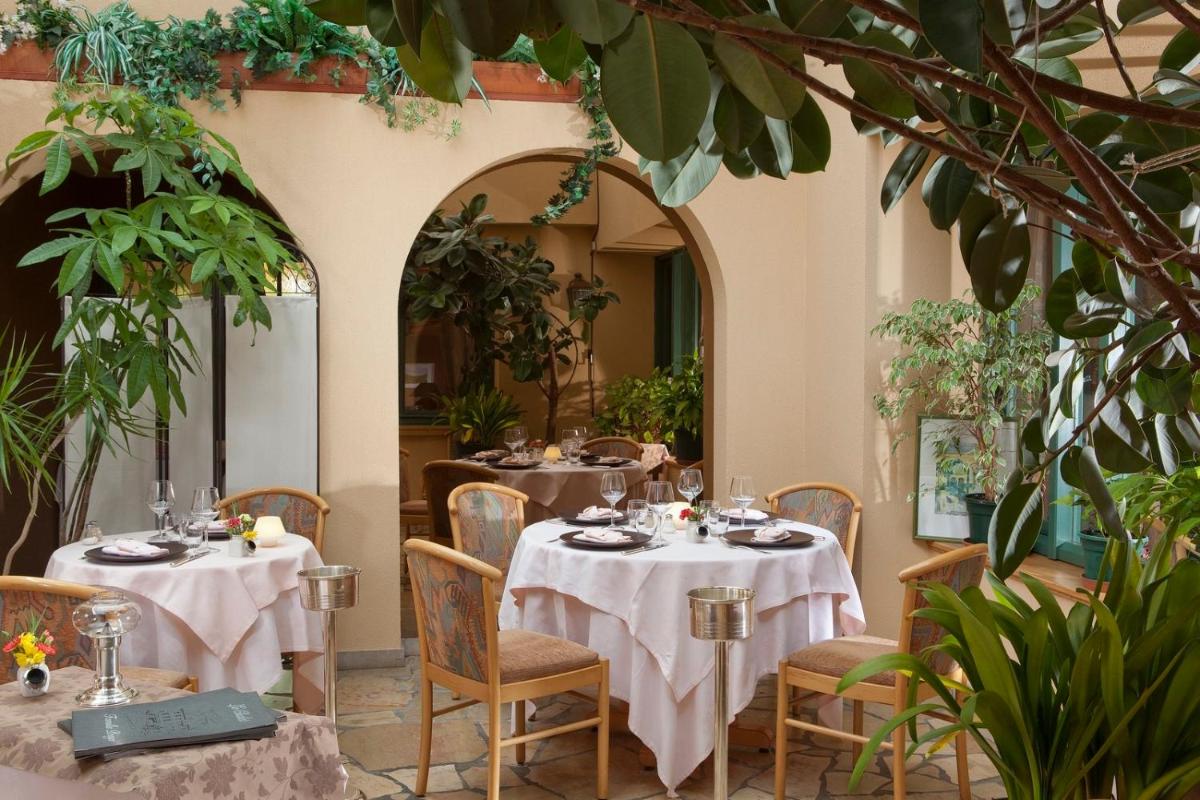 un restaurant avec deux tables recouvertes de nappes blanches dans l'établissement Hotel le Chalet, à Gresse-en-Vercors