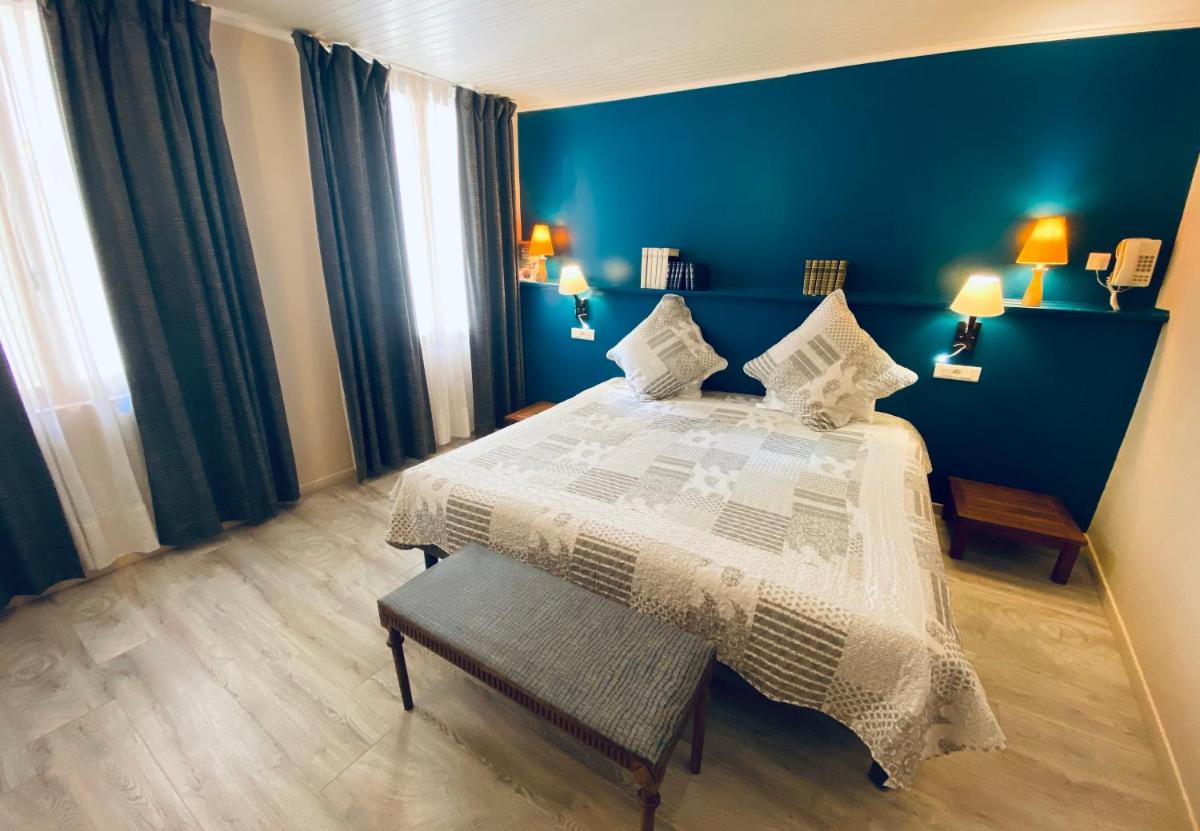 une chambre avec un lit et un mur bleu dans l'établissement Les Arcades Le Lion D'or, à Buis-les-Baronnies 59 autres photos